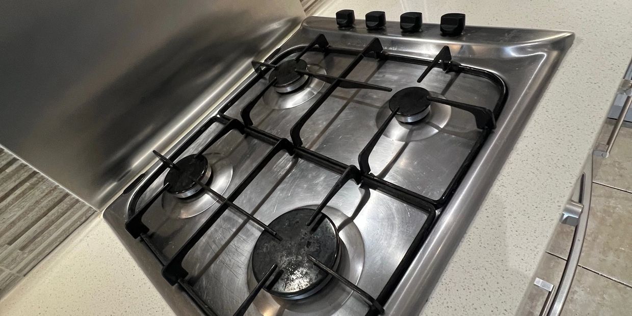 A stainless steel gas stove with four burners and black grates.