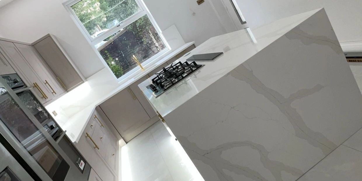 Modern kitchen with marble countertops and gold handles.
