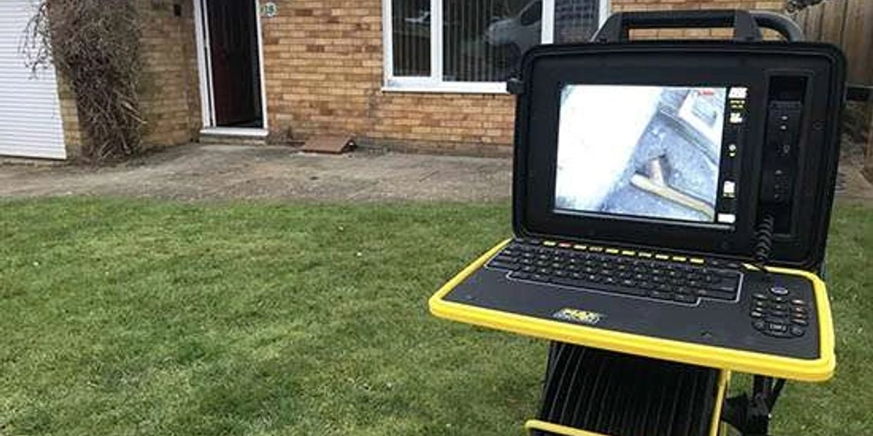Inspection device with screen displaying internal view outside a brick house.