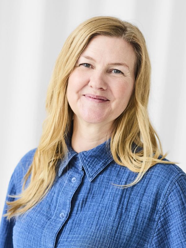 Smiling woman with long blonde hair in a blue shirt.