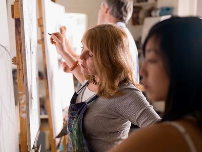 People focused on painting on canvases in an art class.