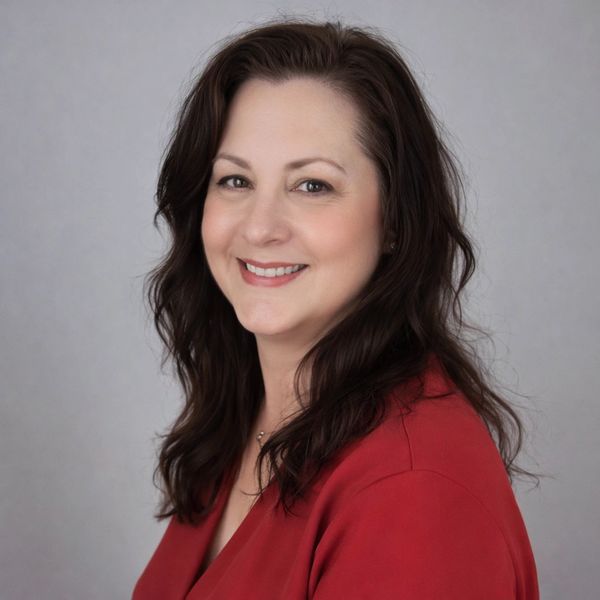 Smiling woman with dark hair in a red top against a gray background.