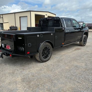 Black utility truck parked near a warehouse.