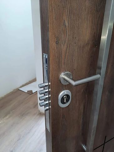 Close-up of a wooden door with a modern metal lock and handle.