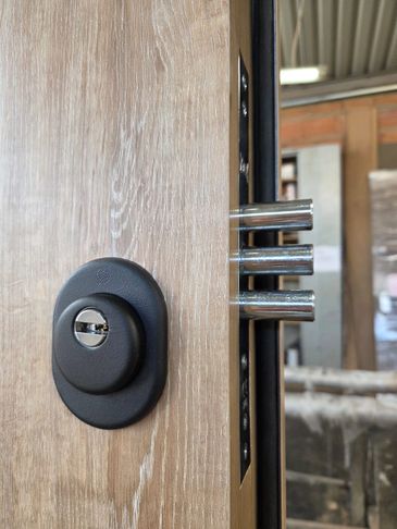 Close-up of a wooden door with a modern security lock and metal bolts.