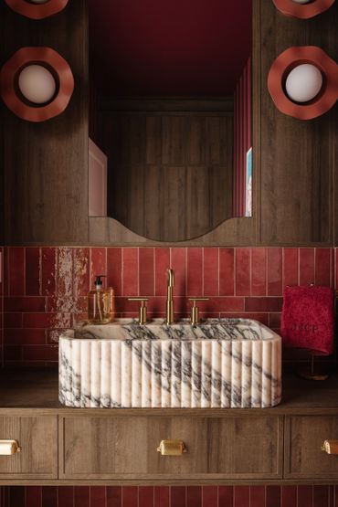 Elegant bathroom sink with marble basin and red tiles.