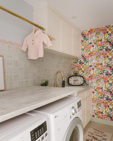 Laundry room with floral wallpaper and modern appliances.