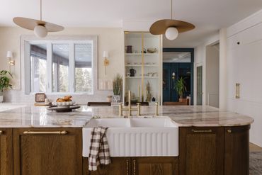 Modern kitchen with marble countertops and a farmhouse sink.