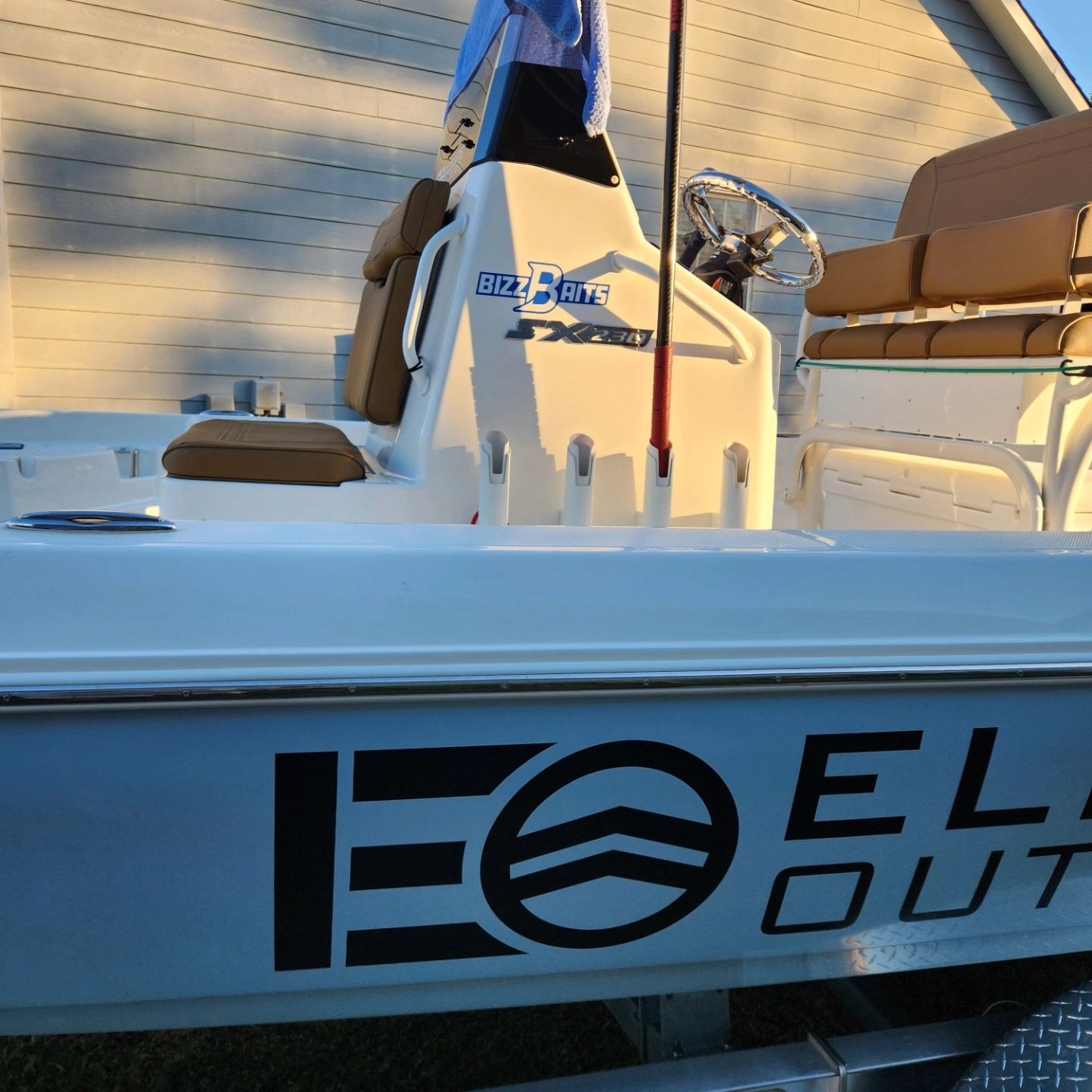 Side view of a fishing boat with beige seats and fishing rod holders.