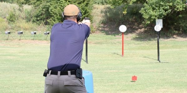 A person aiming a handgun at a shooting range target.