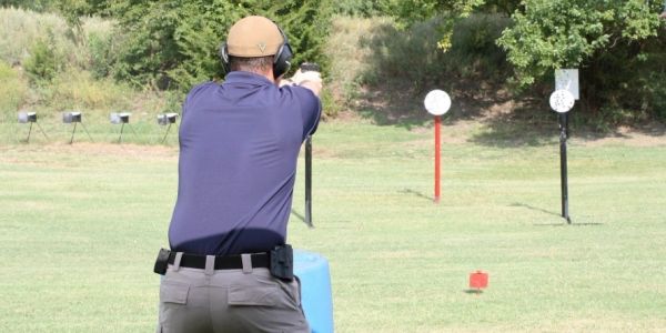 A person aiming a handgun at a shooting range target.