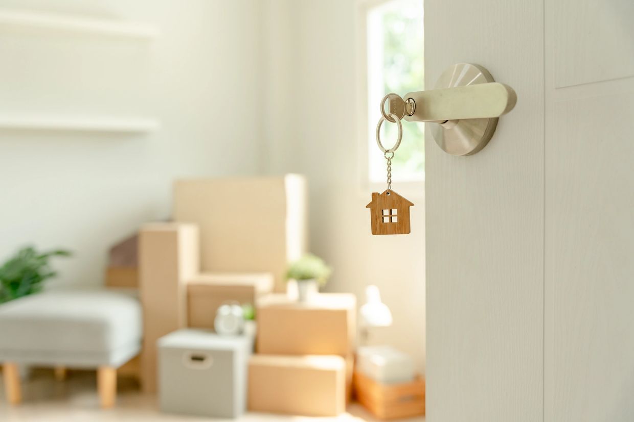 House key with wooden house keychain hanging on door handle.