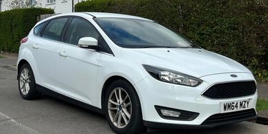 White Ford Focus hatchback parked on a residential street.