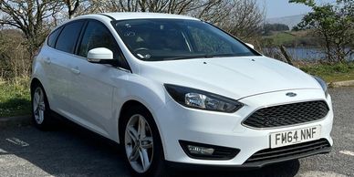 White Ford Focus hatchback parked outdoors on a sunny day.