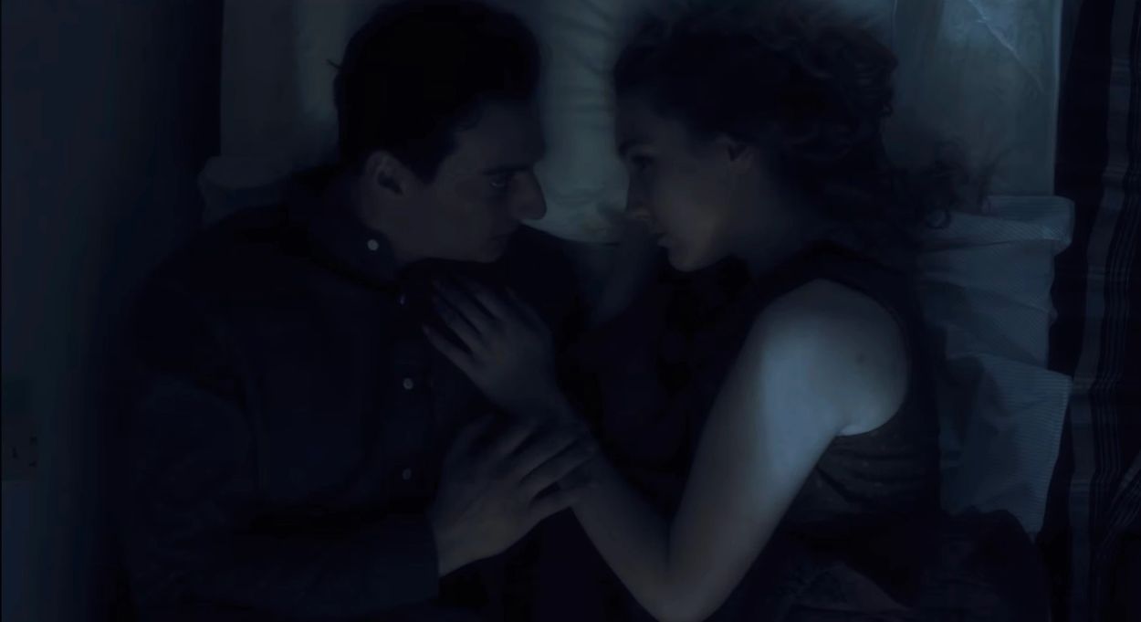 Couple lying together in bed, sharing an intimate moment.