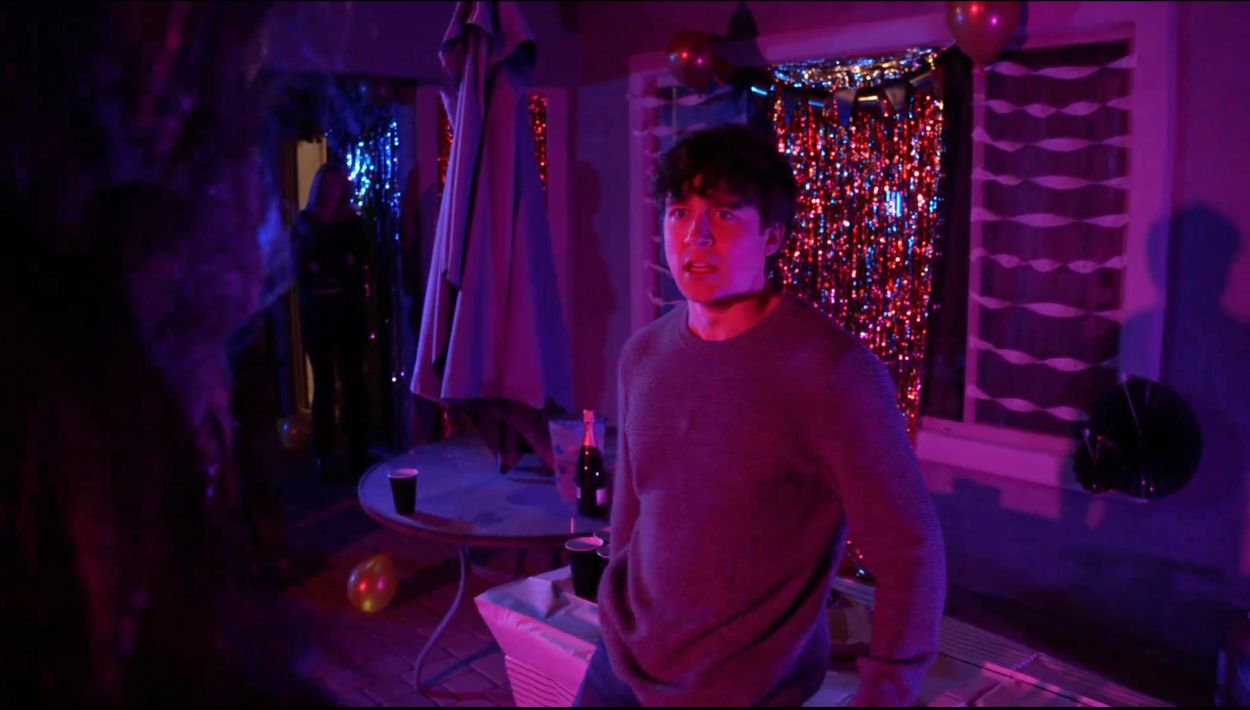 Young man looks surprised at a neon-lit party.
