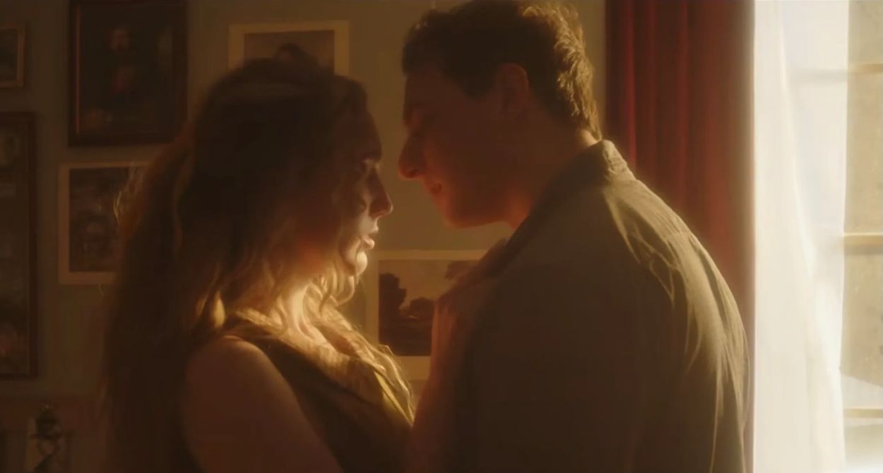 A couple shares a tender moment bathed in warm light.