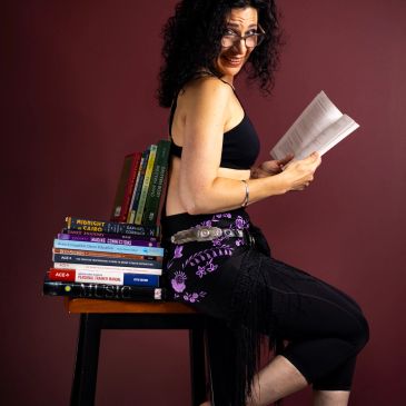 Woman sitting on books reading.