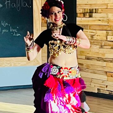 Woman dancing in colorful traditional attire with a big smile.