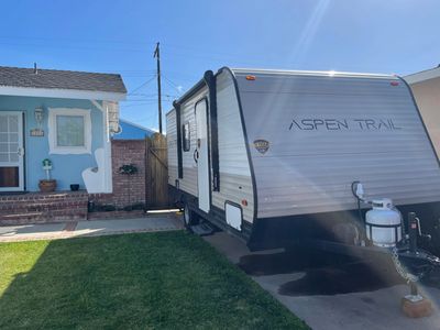 Travel trailer parked by a house on a sunny day.