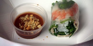 Vietnamese spring roll with peanut dipping sauce on a white plate.