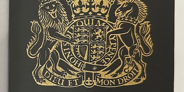 Gold embossed Royal Coat of Arms on black background.