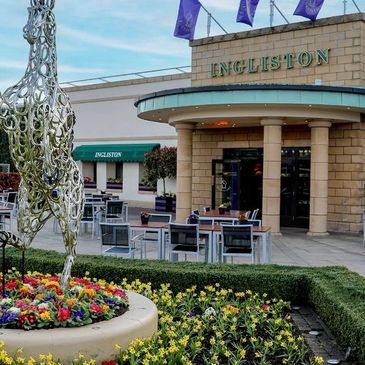 Outdoor dining area at Ingliston with metal sculpture and flower beds.