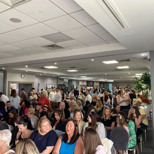 A crowded indoor event with many people seated and standing.