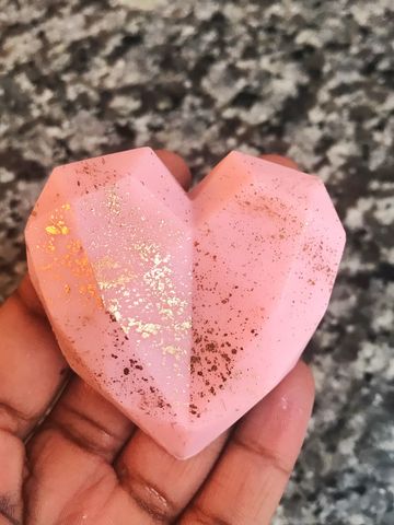 Cake encased in a pink heart-shaped chocolate shell with rose gold edible paint splattered on it.