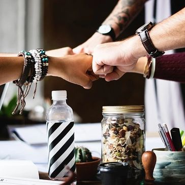 five people bringing hands together at a table 