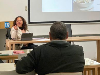 Woman presenting to an audience in a classroom setting.