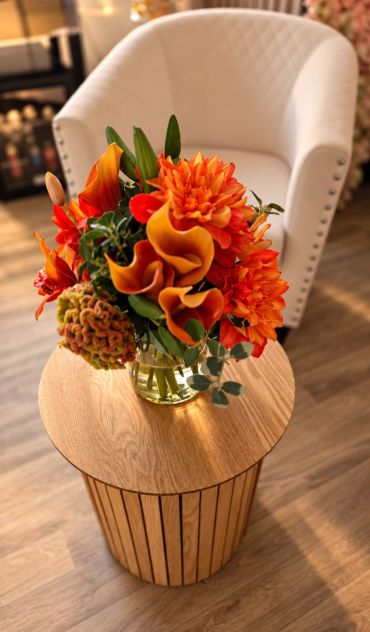 Bright orange flowers in a glass vase on a wooden table.