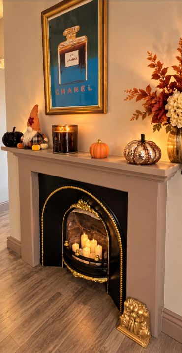 Autumn-themed mantel with candles, pumpkins, and flowers.