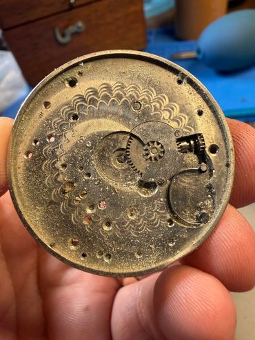 Close-up of a vintage watch mechanism with visible gears and intricate patterns.