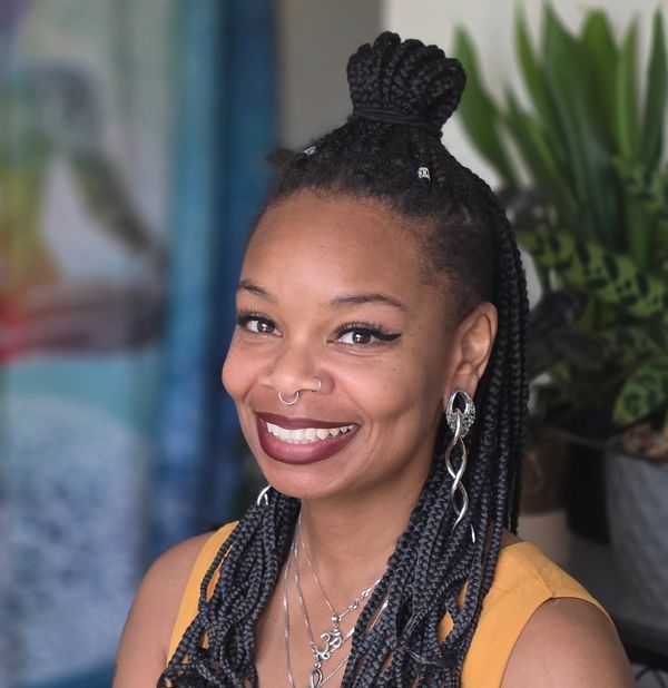 Young woman with braided hair smiling warmly.