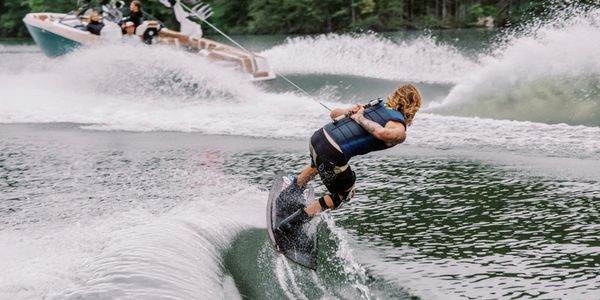 Person wakeboarding on a lake, holding a tow rope attached to a boat.