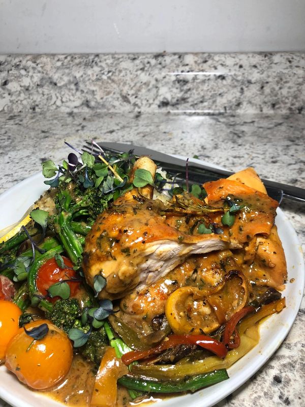 Plate of grilled chicken with vegetables and sauce on a white plate.
