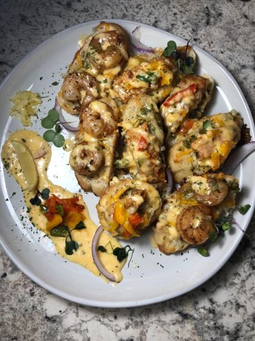 Plate of cheesy baked seafood-stuffed shells garnished with herbs and vegetables.