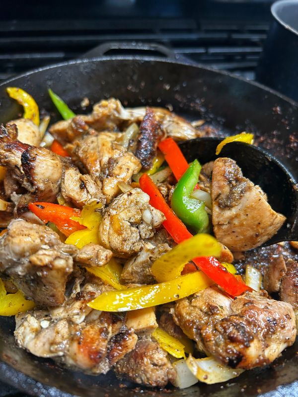 Sizzling chicken stir-fry with colorful bell peppers in a cast iron skillet.