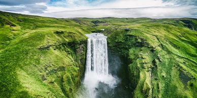 A waterfall in verdant countryside in Iceland.