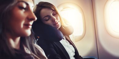 A woman sleeping on a flight, with help from her travel pillow.