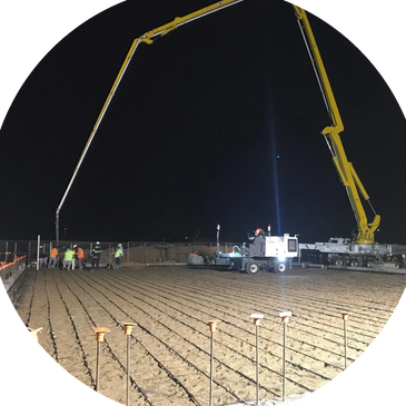 Monroy Construction's crew pouring out a large commercial slab with a concrete pump at night.
