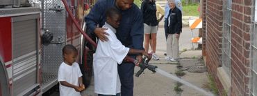 Adult helping a child with a fire hose