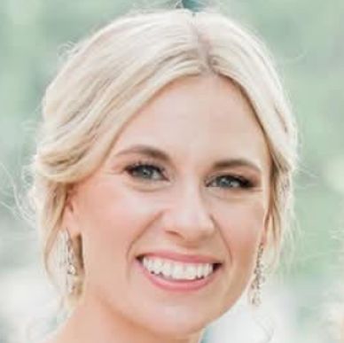 Close-up of a smiling woman with blonde hair and elegant earrings.