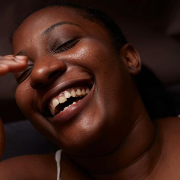 Close-up of a joyful woman laughing with eyes closed.