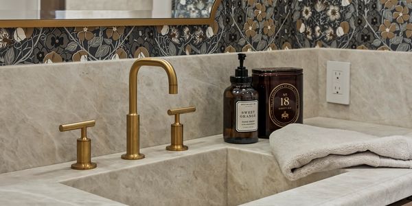 Modern bathroom sink with gold fixtures and decorative soap dispenser.
