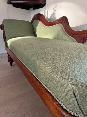 Green upholstered vintage wooden sofa with elegant design.