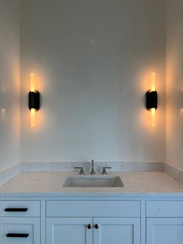 Minimalist bathroom sink with modern lighting and white cabinetry.