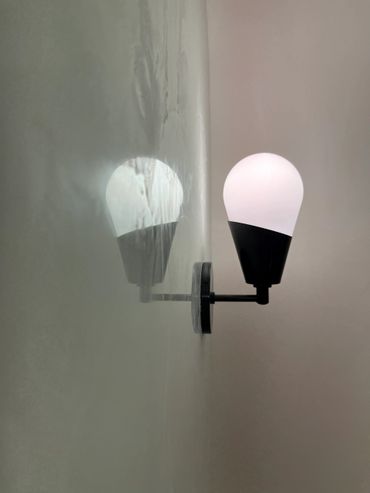 Modern wall lamp casting a soft glow and reflection on the wall.