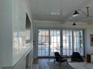 Modern living room with black chairs and large glass doors opening to a pool.